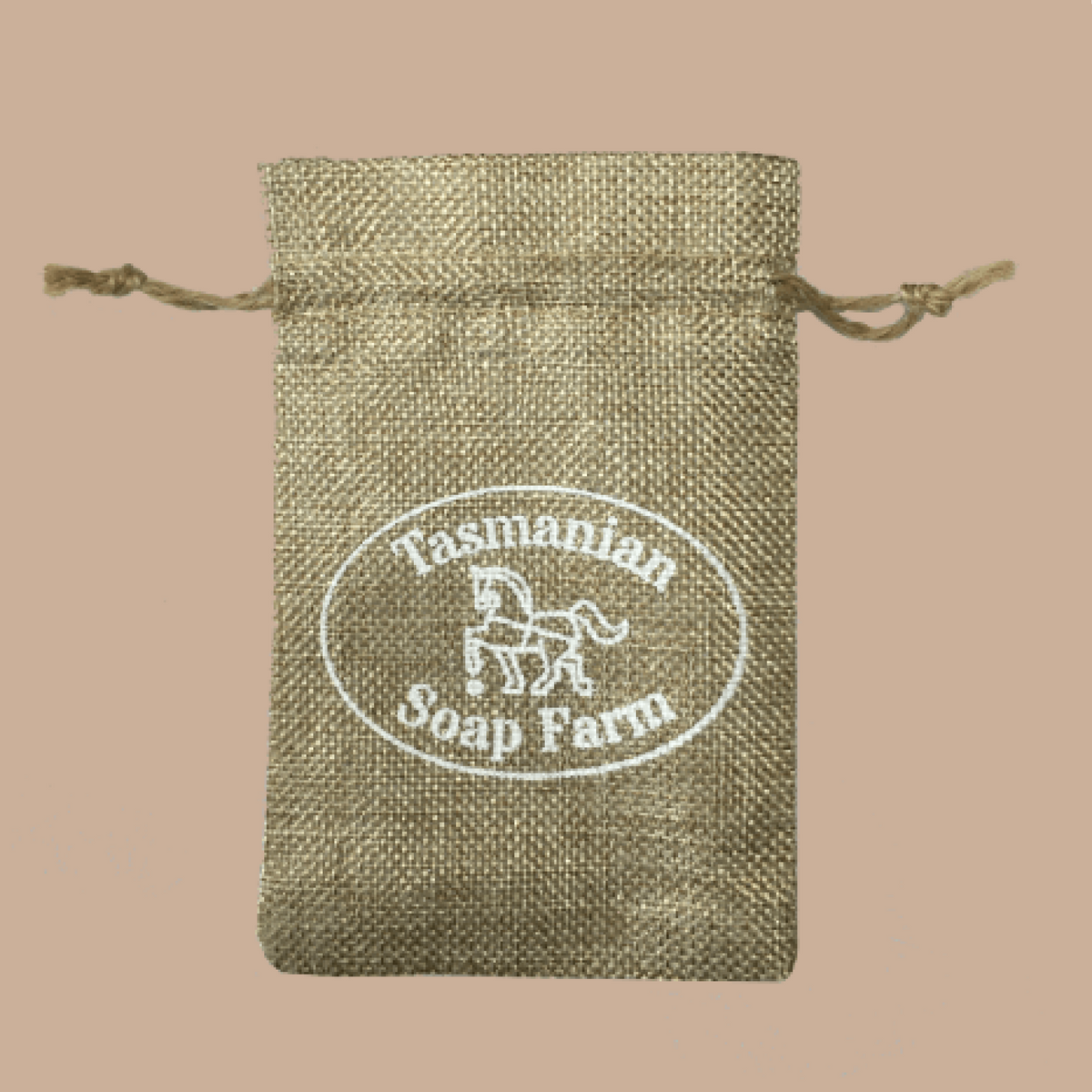 A small natural jute drawstring pouch with a white printed oval logo reading 'Tasmanian Soap Farm' on a solid beige background.
