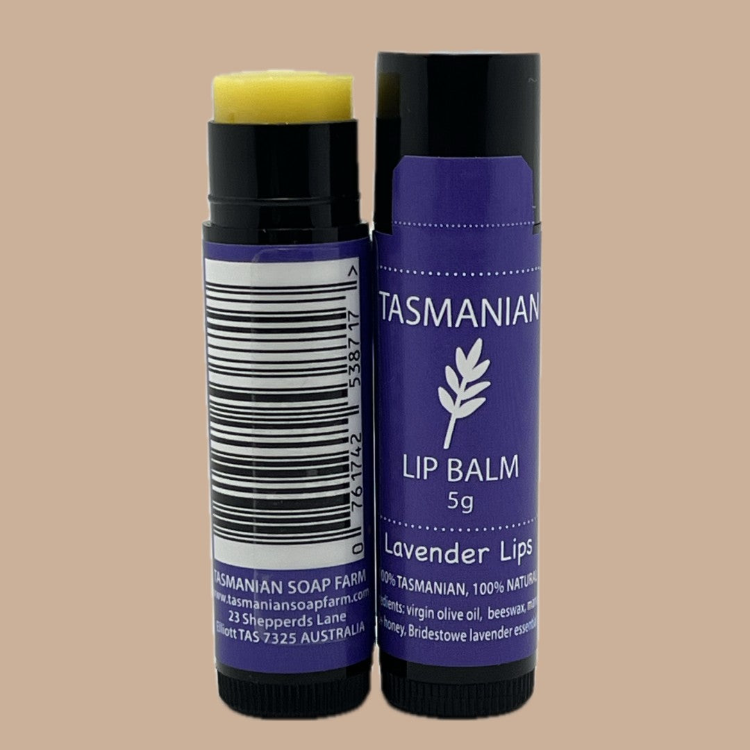 Two tubes of Tasmanian Soap Farm 'lavender lips' Lip Balm, one showing the yellow balm stick and the other showing the purple tube with a barcode label, on a solid beige background.