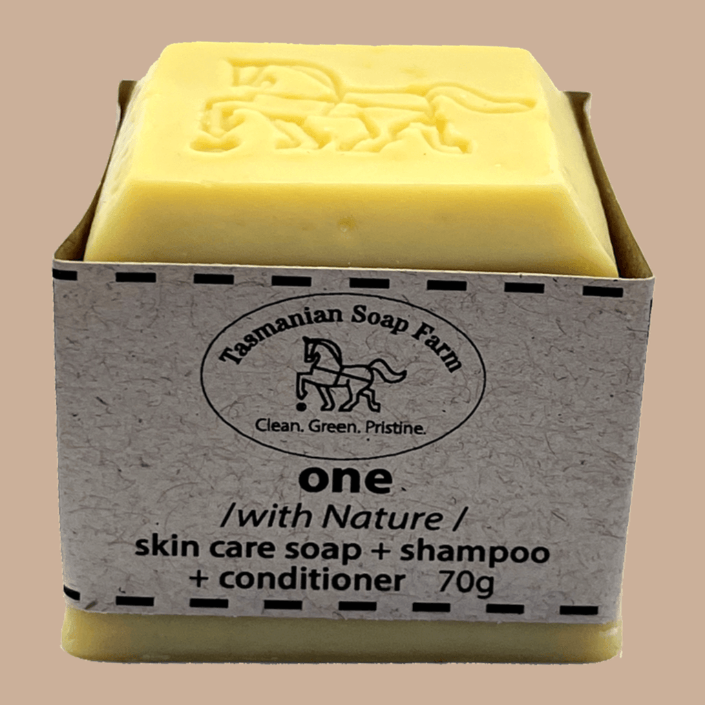 A 70g bar of Tasmanian Soap Farm 'one' skin care soap and shampoo set, featuring a pale yellow bar of soap and shampoo wrapped in a textured gray paper sleeve with a horse logo.