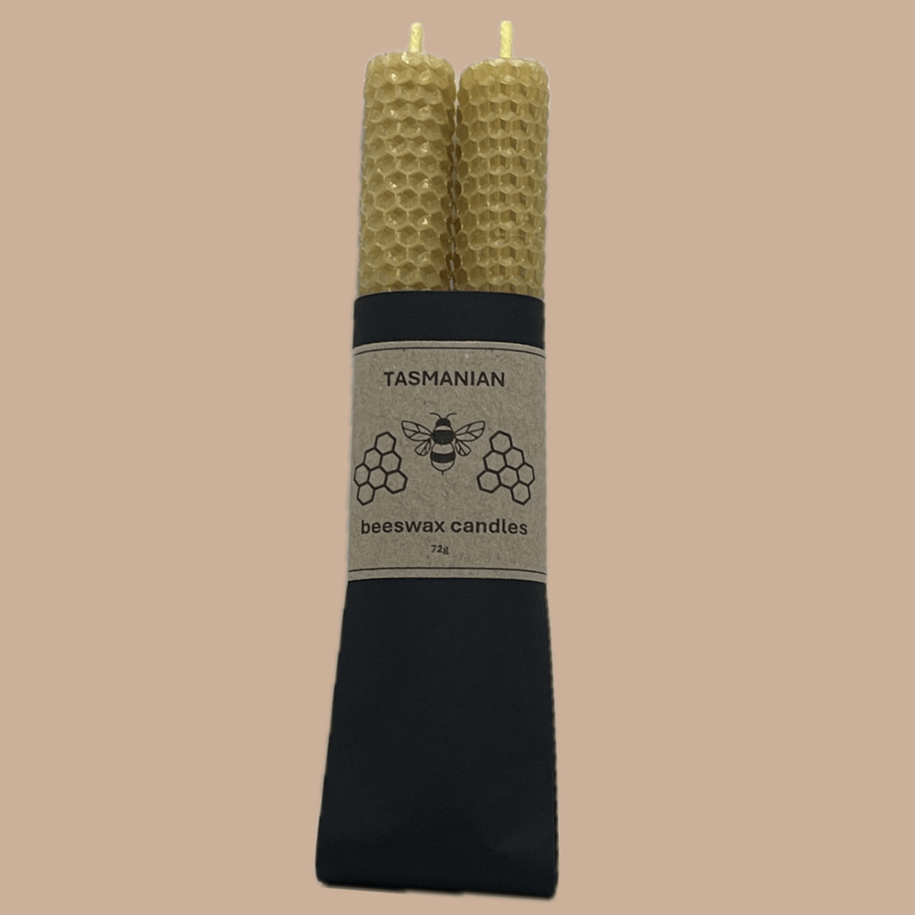 Two natural honeycomb beeswax candles standing upright in a black paper sleeve with a beige label that reads 'TASMANIAN beeswax candles'.