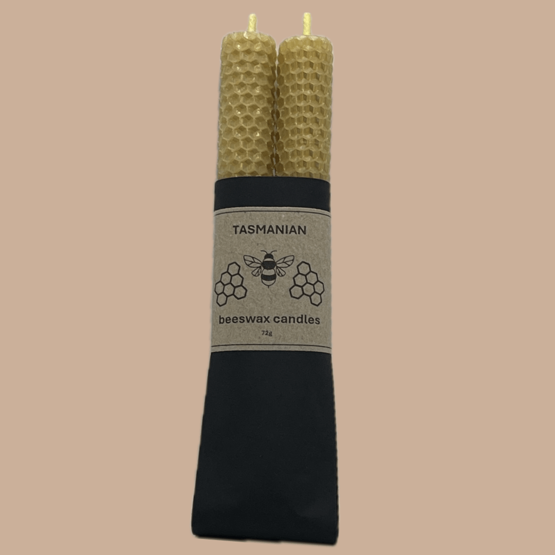 Two natural honeycomb beeswax candles standing upright in a black paper sleeve with a beige label that reads 'TASMANIAN beeswax candles'.