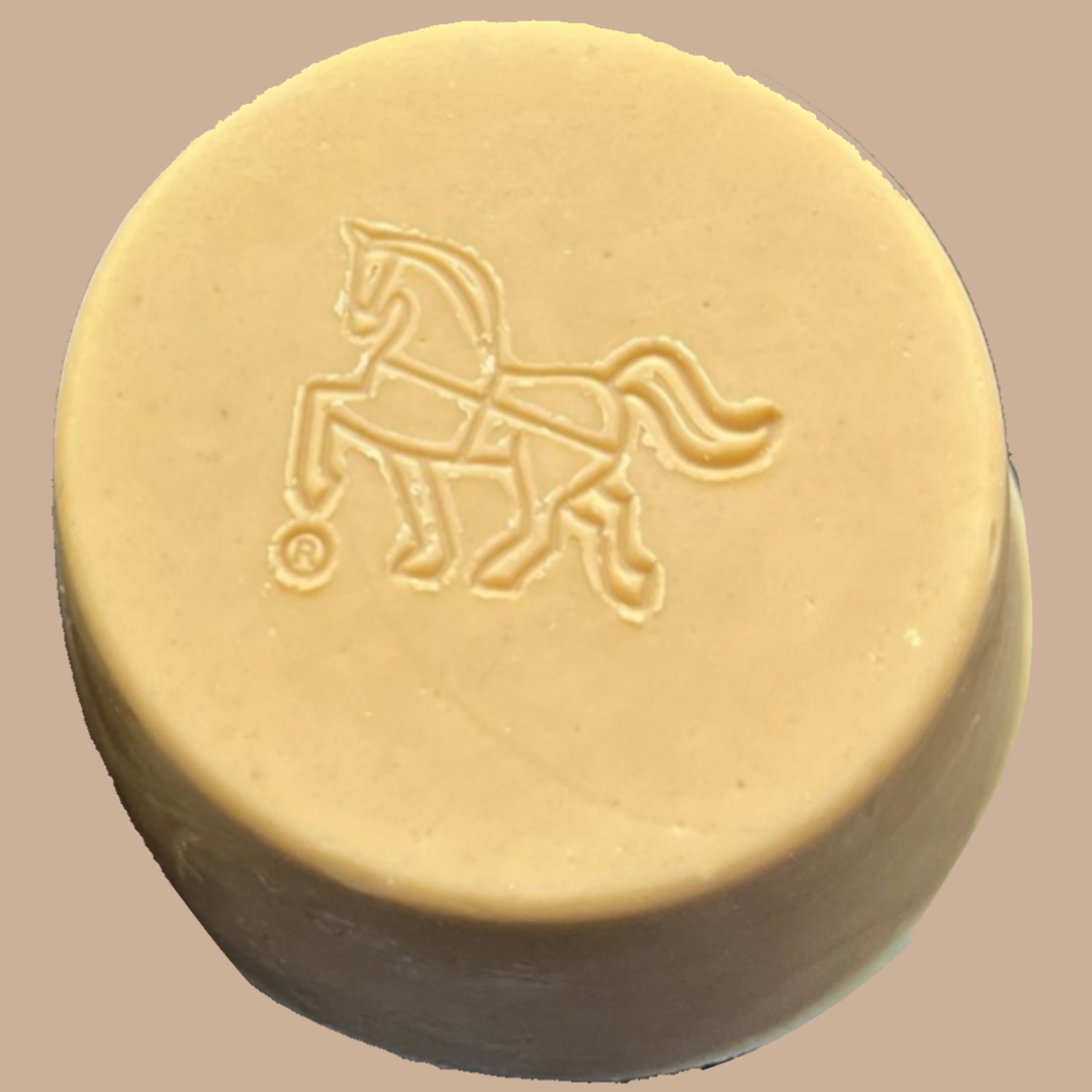 A round, light tan bar of Tasmanian Soap Farm doggo soap with an embossed horse logo, shown against a solid taupe background.
