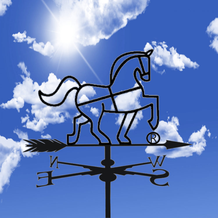 A black metal horse weather vane with directional arrow and compass rose, shown against a bright blue sky with white clouds and sun. The horse is the Tasmanian Soap Farm logo horse.
