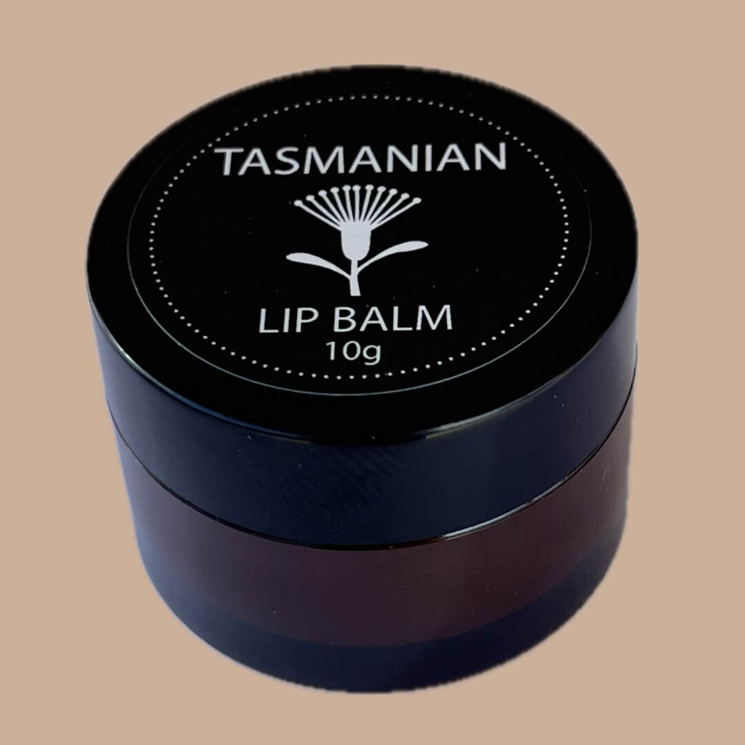 A 10g jar of Tasmanian Lip Balm with a black lid featuring a white kunzea flower logo and text, set against a solid beige background.