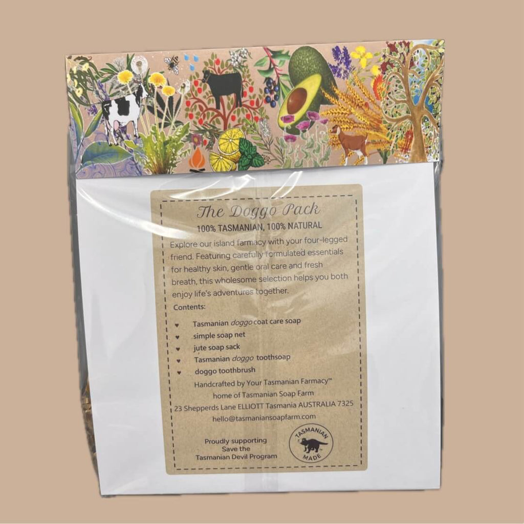 A packaged product labeled 'The Doggo Pack' in a clear plastic bag with a colorful illustrated header card. The card features whimsical drawings of a goat, avocado, flowers, and a tree, while the front insert card is kraft with black text detailing contents and product information.