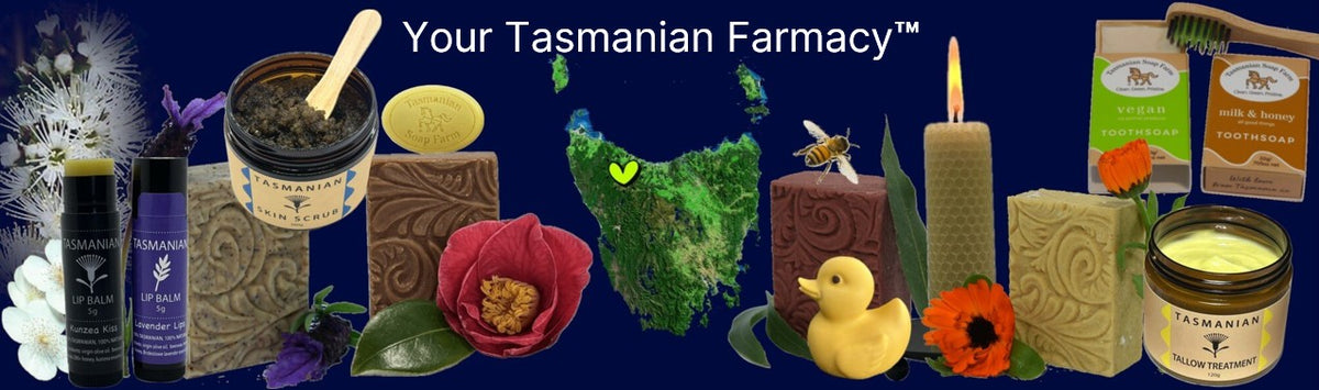 A promotional banner for Tasmanian Soap Farm products on a dark blue sea background, featuring skin care items such as soap bars, candles, a jar of cream, and bottles, alongside decorative elements including a green map outline of Tasmania, a yellow soap duck, and flowers.